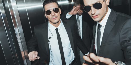 bodyguards-stopping-paparazzi-and-celebrity-covering-face-with-hand-in-elevator-scaled-1.jpg bodyguards-stopping-paparazzi-and-celebrity-covering-face-with-hand-in-elevator-scaled-1.jpg