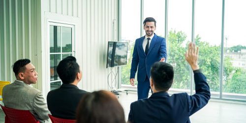 Raised up hands and arms of large group in seminar class room to agree with speaker at conference seminar Raised up hands and arms of large group in seminar class room to agree with speaker at conference seminar